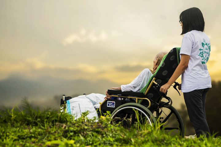 aged woman in a wheelchair being assisted